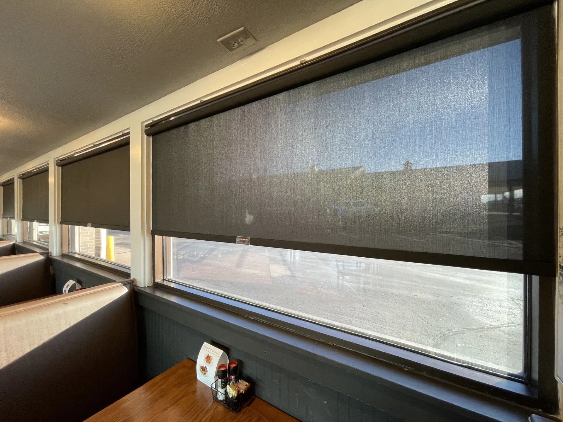 Solar shades on a window halfway open above a table